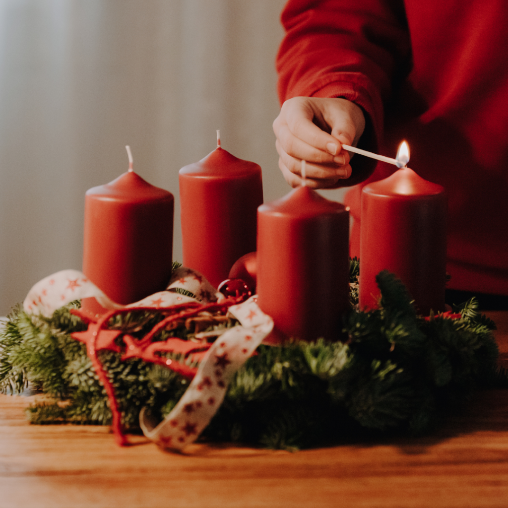 Mann zündet die erste Kerze des Adventskranzes an